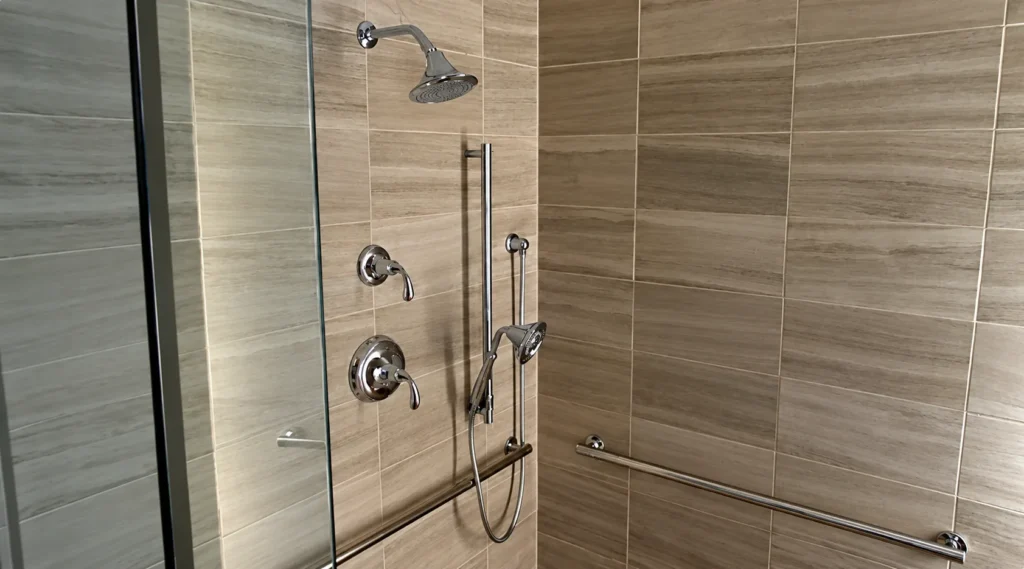 Accessible shower with chrome fixtures, handheld shower head and grab bar